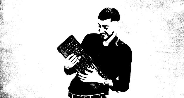 Schwarzweiß-Foto eines Mitarbeiters mit Tastatur, künstlerisch inszeniert wie ein Musikinstrument.