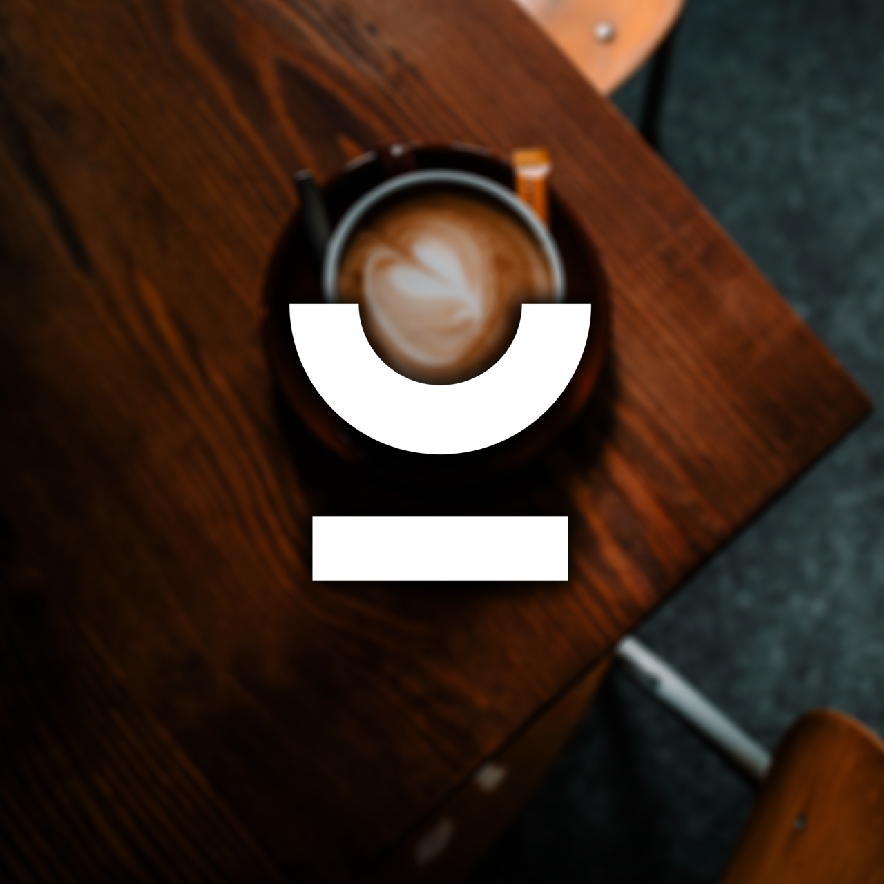 Tasse Cappuccino von oben auf einem Holztisch, darüber das weiße Decide-Logo.