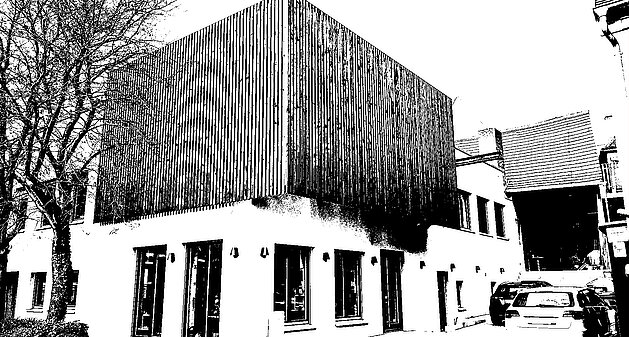 Modernes zweistöckiges Firmengebäude mit Holzlamellen-Fassade und großen Fenstern, davor geparkte Autos.
